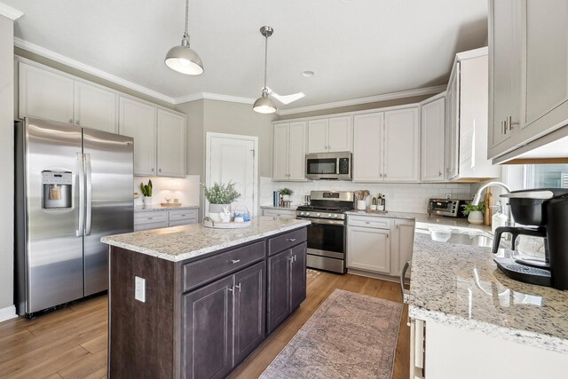 kitchen with crown molding, a kitchen island, tasteful backsplash, a sink, and appliances with stainless steel finishes