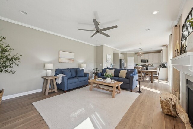 living area featuring crown molding, baseboards, ceiling fan, light wood-type flooring, and recessed lighting