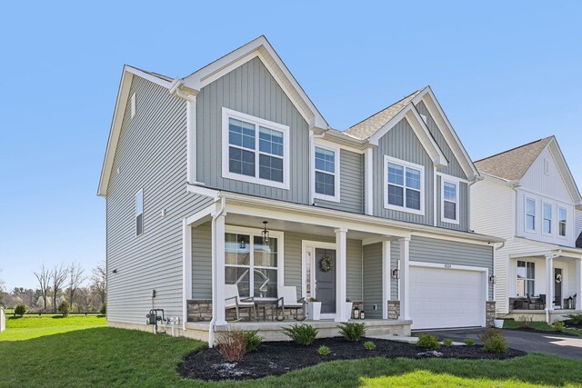 craftsman-style home featuring a garage, covered porch, a front yard, board and batten siding, and driveway