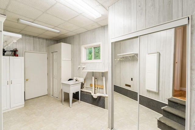 interior space featuring wooden walls, tile patterned floors, and a drop ceiling