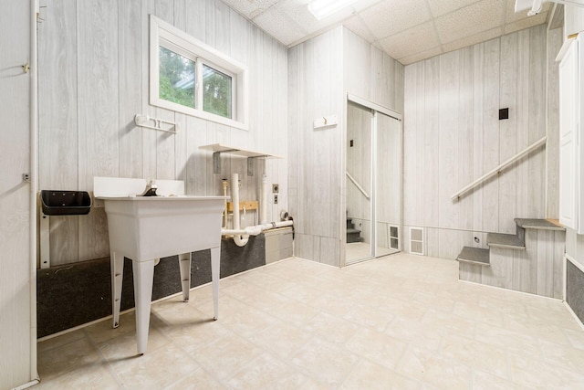 miscellaneous room with wood walls, tile patterned floors, and stairway