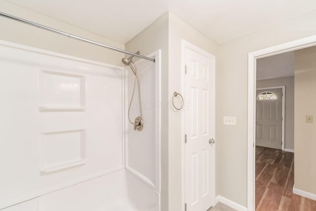 bathroom featuring a shower, baseboards, and wood finished floors