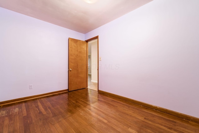 empty room with baseboards and hardwood / wood-style flooring