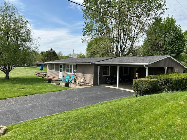 rear view of house with aphalt driveway, a yard, and a carport