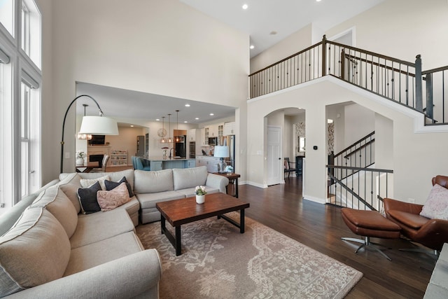 8153 Lilium Way, Plain City, OH 43064 - living area featuring stairway, dark wood-style floors, arched walkways, recessed lighting, and a high ceiling