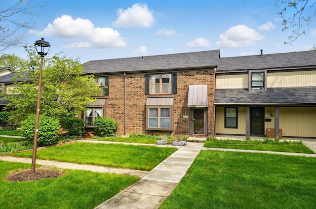 townhome / multi-family property with a front yard and brick siding