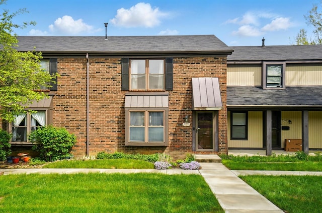 view of property with brick siding and a front lawn