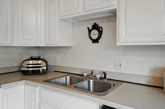 kitchen with a sink, white cabinets, and light countertops