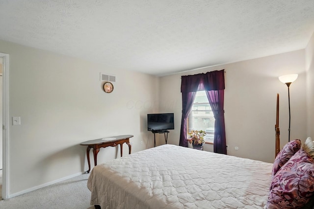 bedroom with a textured ceiling, visible vents, baseboards, and carpet floors