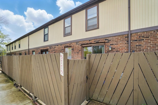 view of side of property featuring fence and brick siding