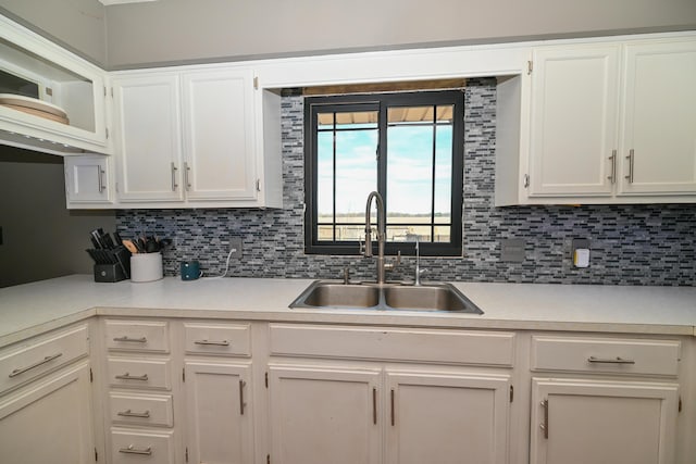 kitchen featuring a sink, backsplash, white cabinets, and light countertops