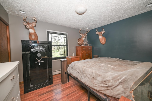 bedroom featuring a textured ceiling, a baseboard radiator, and wood finished floors