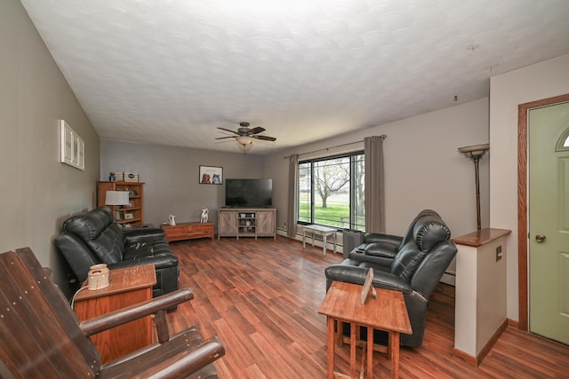 living area with baseboards, a ceiling fan, dark wood finished floors, and a textured ceiling