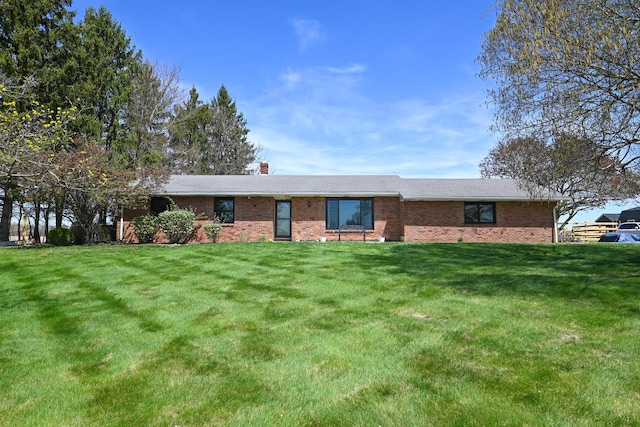 ranch-style house with brick siding, a chimney, and a front yard