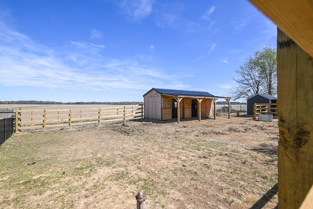 view of yard with an exterior structure, a rural view, and an outbuilding