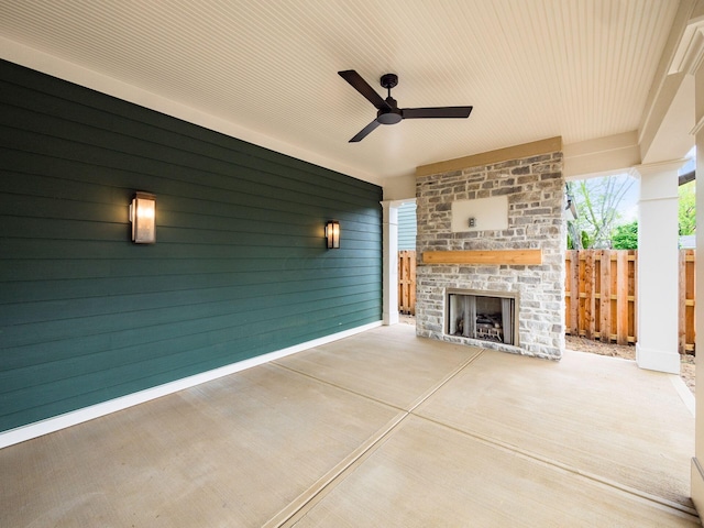 view of patio featuring an outdoor brick fireplace, fence, and ceiling fan