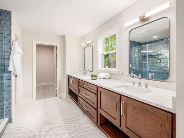 full bath featuring a stall shower, double vanity, and baseboards