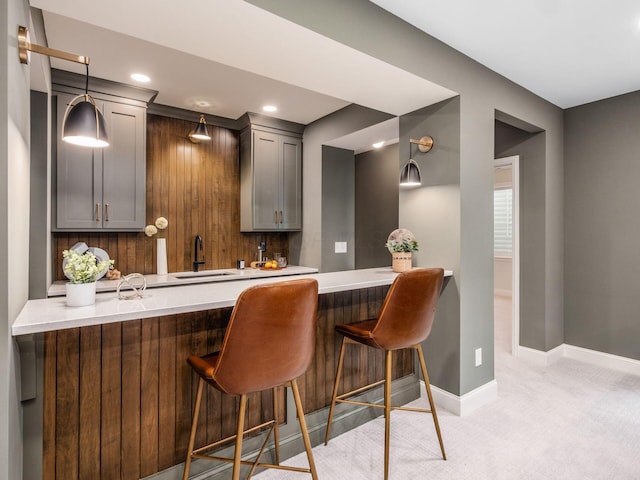 bar with light colored carpet, baseboards, recessed lighting, hanging light fixtures, and a sink