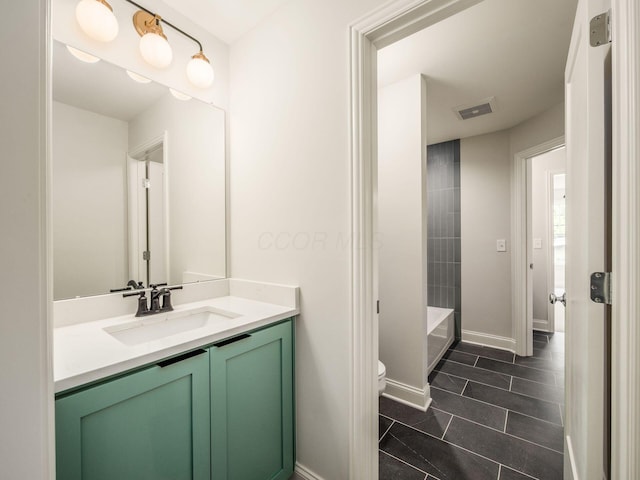 bathroom with vanity, toilet, a bathtub, baseboards, and tile patterned floors