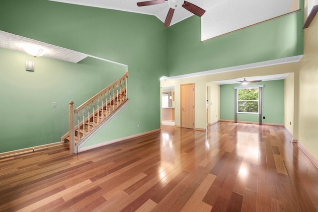 2977 Highwall Way, Columbus, OH 43221 - unfurnished living room featuring a ceiling fan, a towering ceiling, stairs, wood finished floors, and baseboards