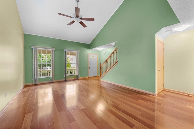 2977 Highwall Way, Columbus, OH 43221 - unfurnished living room with ceiling fan, stairway, baseboards, wood finished floors, and high vaulted ceiling
