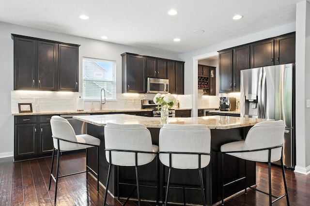 298 Long Branch Run, Delaware, OH 43015 - kitchen with appliances with stainless steel finishes, a kitchen island, light stone countertops, a kitchen bar, and tasteful backsplash