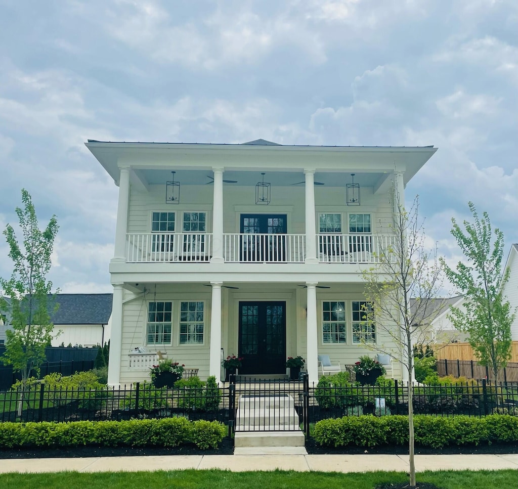 view of front of home with a porch, french doors, a fenced front yard, a gate, and a balcony