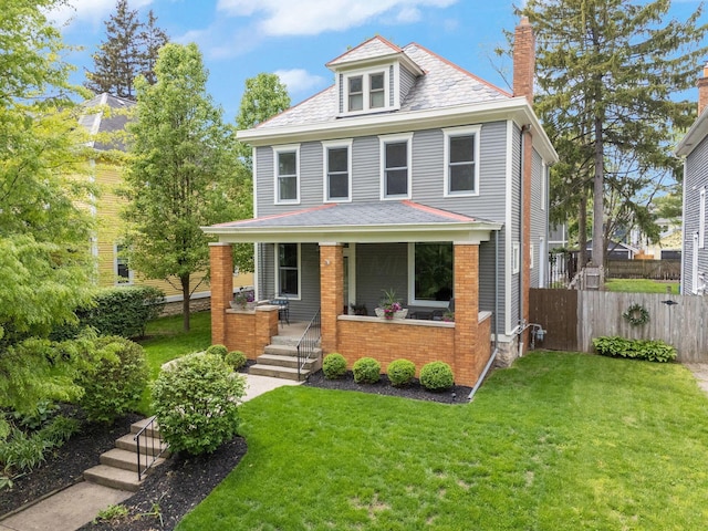 american foursquare style home with a front yard, fence, covered porch, and a chimney