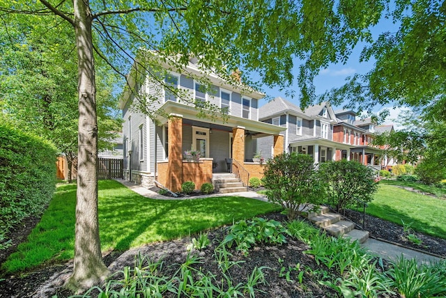 american foursquare style home with a porch, a front lawn, fence, and brick siding