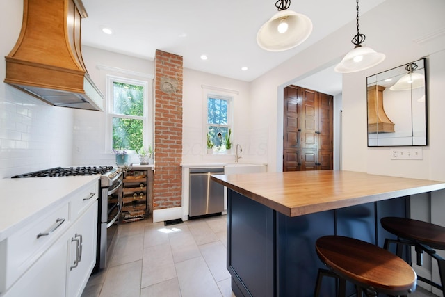 kitchen with a breakfast bar, stainless steel appliances, white cabinetry, wine cooler, and custom exhaust hood