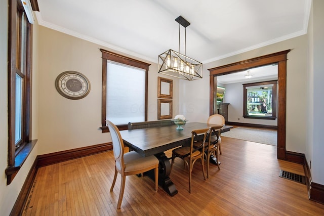 dining space featuring visible vents, crown molding, baseboards, a notable chandelier, and hardwood / wood-style floors