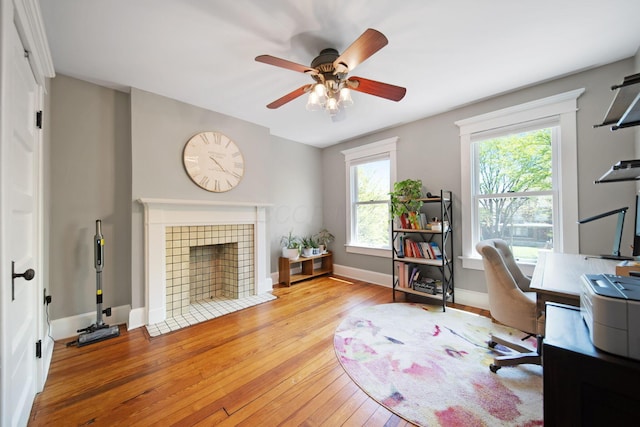 office space featuring wood-type flooring, ceiling fan, baseboards, and a fireplace
