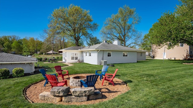 rear view of house with a fire pit, a yard, and a chimney