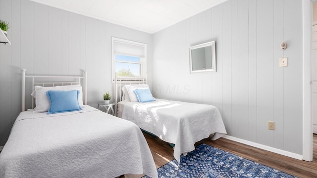bedroom with baseboards, ornamental molding, and wood finished floors