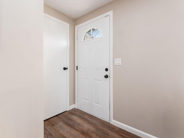 doorway to outside featuring baseboards and dark wood finished floors