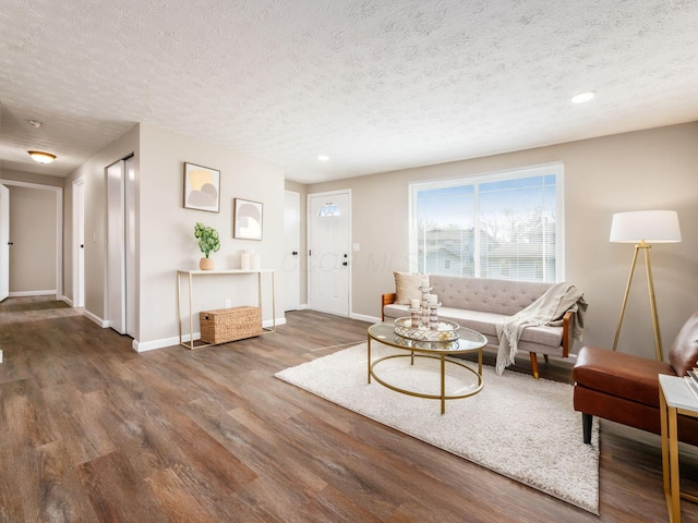 living area featuring a textured ceiling, wood finished floors, and baseboards