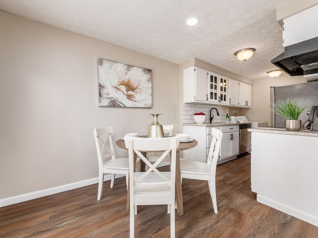 kitchen with white cabinetry, light countertops, baseboards, dishwasher, and dark wood finished floors
