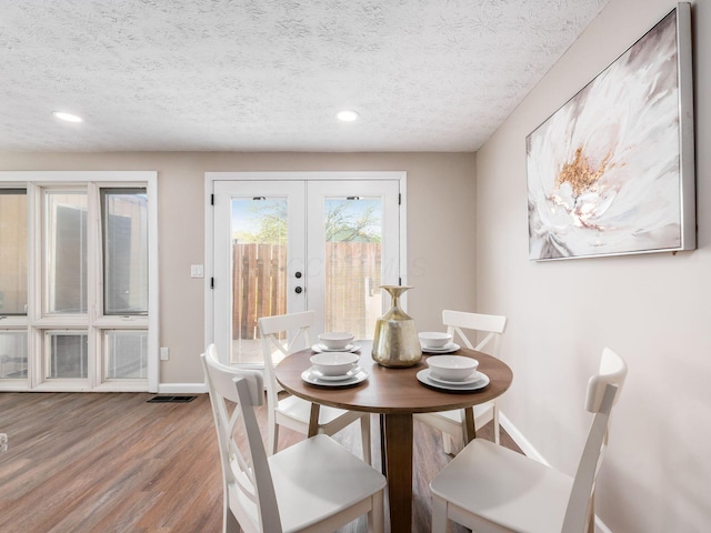 dining area with recessed lighting, wood finished floors, baseboards, a textured ceiling, and french doors