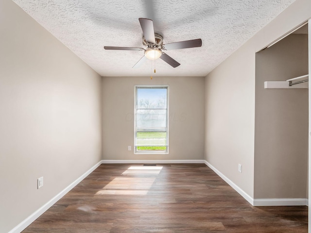 empty room featuring a ceiling fan, baseboards, wood finished floors, and a textured ceiling