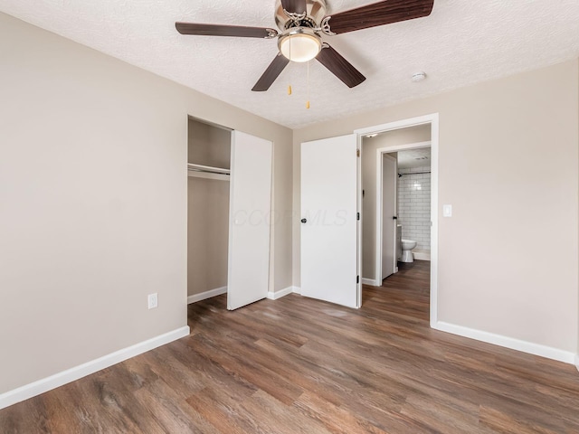 unfurnished bedroom featuring a textured ceiling, a closet, wood finished floors, and baseboards