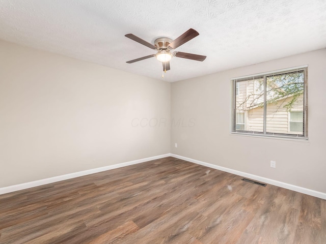 unfurnished room featuring wood finished floors, visible vents, ceiling fan, and baseboards