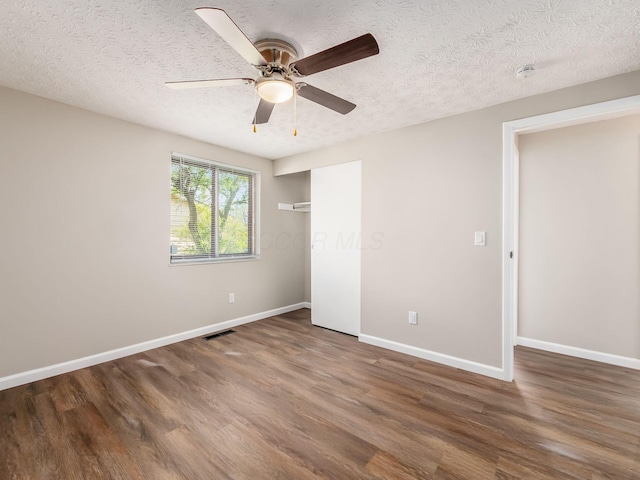 unfurnished bedroom featuring a textured ceiling, wood finished floors, and baseboards