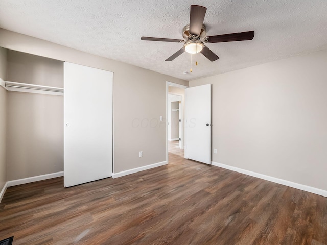 unfurnished bedroom featuring a textured ceiling, a closet, wood finished floors, and baseboards