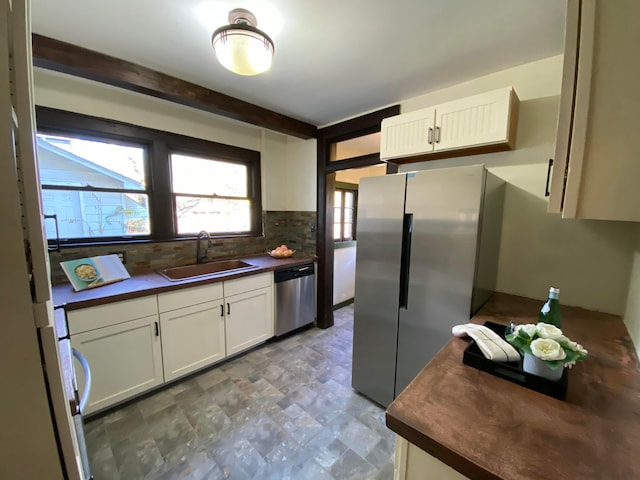 110 N Ogden Ave, Columbus, OH 43204 - kitchen with white cabinetry, decorative backsplash, a sink, appliances with stainless steel finishes, and dark countertops