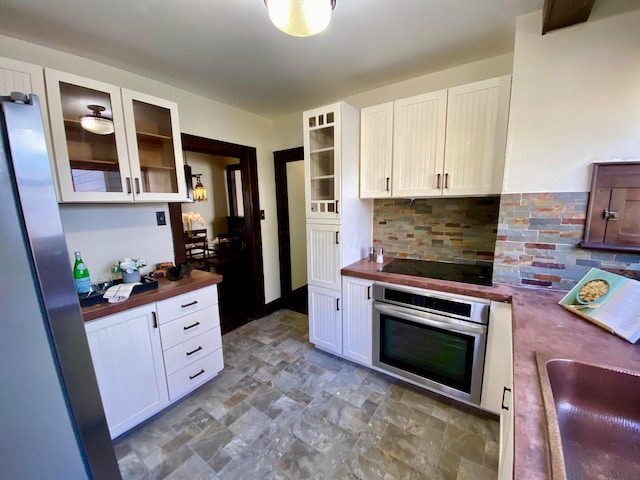 110 N Ogden Ave, Columbus, OH 43204 - kitchen with black electric stovetop, stone finish flooring, butcher block countertops, stainless steel oven, and backsplash