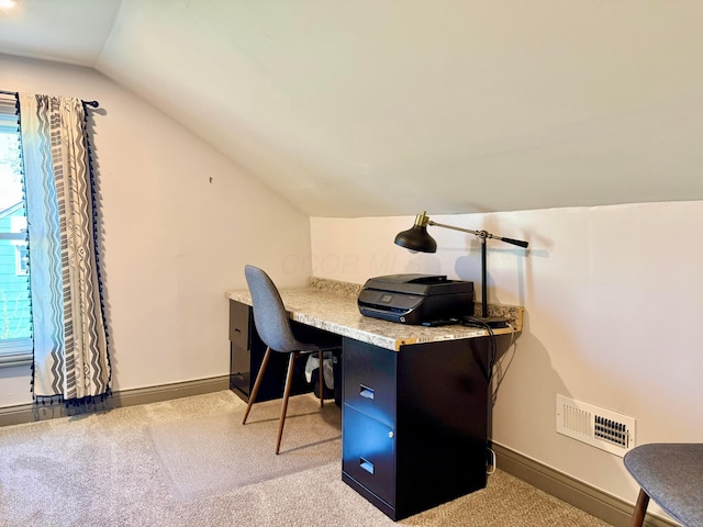 office area with visible vents, baseboards, vaulted ceiling, and light carpet