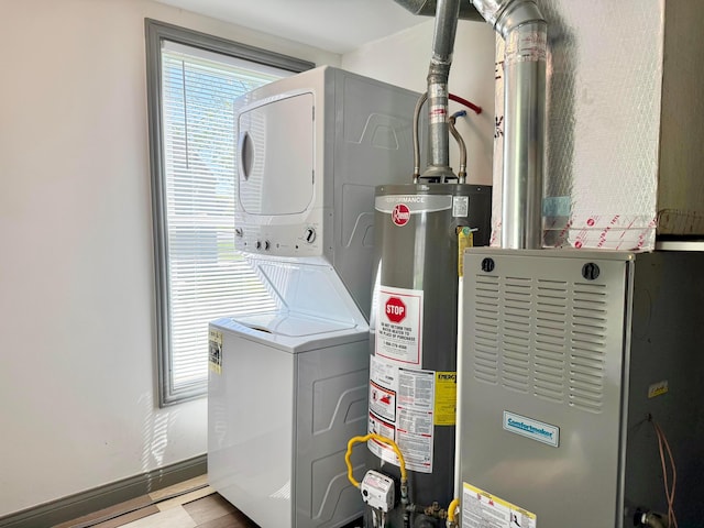 utility room featuring gas water heater, stacked washer / drying machine, and heating unit