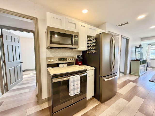 kitchen featuring white cabinets, visible vents, appliances with stainless steel finishes, and light wood-style flooring