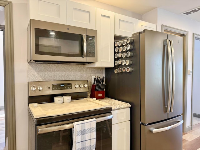 kitchen featuring tasteful backsplash, visible vents, appliances with stainless steel finishes, and white cabinetry