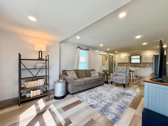 living area with baseboards, recessed lighting, and light wood-style floors